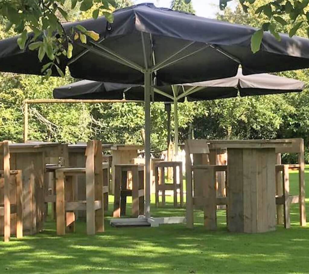 steigerhouten staantafels en krukken in tuin met parasol